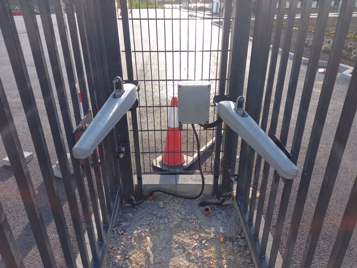 Dva pogona na krilima metalne kapije i upravljačka kutija između njih.